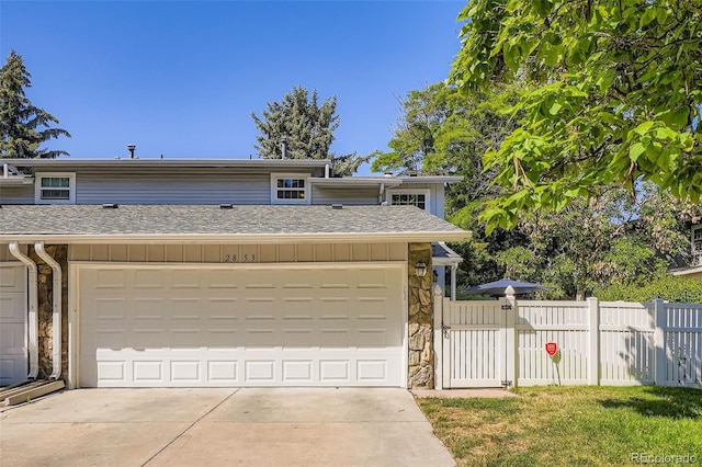 2853 S Xanadu Way, Aurora, CO 80014 - view of front facade with stone siding, board and batten siding, driveway, and a shingled roof