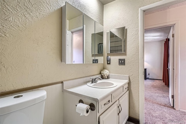 2853 S Xanadu Way, Aurora, CO 80014 - bathroom with a textured wall, vanity, and a wainscoted wall
