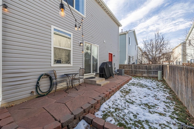 snow covered patio with central AC unit and grilling area