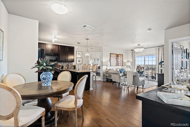 dining room featuring visible vents, dark wood-style flooring, and a textured ceiling