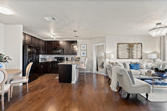 kitchen with visible vents, black appliances, open floor plan, and an inviting chandelier