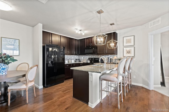 kitchen featuring visible vents, dark brown cabinets, black appliances, and decorative backsplash