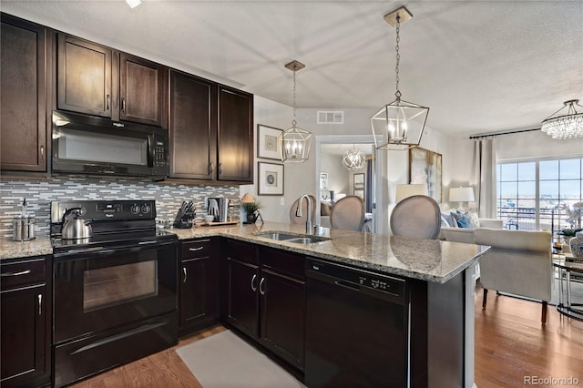 kitchen featuring visible vents, a chandelier, open floor plan, black appliances, and a sink