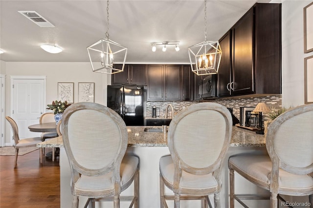 kitchen featuring visible vents, dark brown cabinets, freestanding refrigerator, and an inviting chandelier