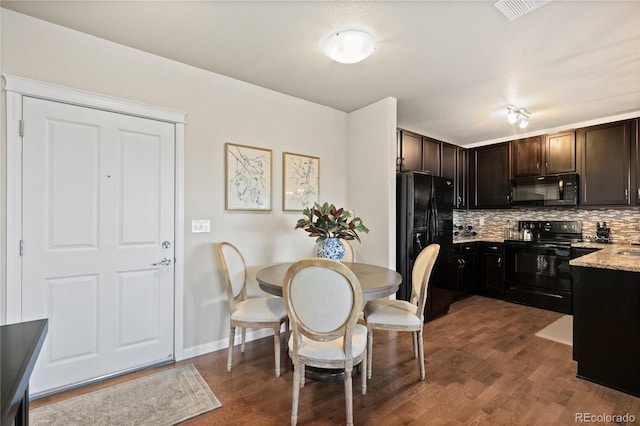 kitchen featuring light stone counters, dark wood-style floors, decorative backsplash, black appliances, and dark brown cabinets