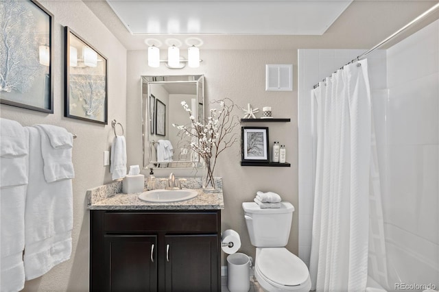 bathroom featuring vanity, a shower with shower curtain, visible vents, toilet, and a textured wall