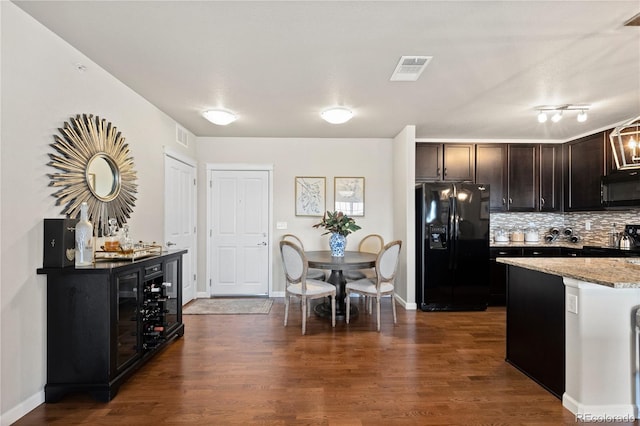 kitchen featuring visible vents, dark wood-style flooring, decorative backsplash, black appliances, and dark brown cabinets