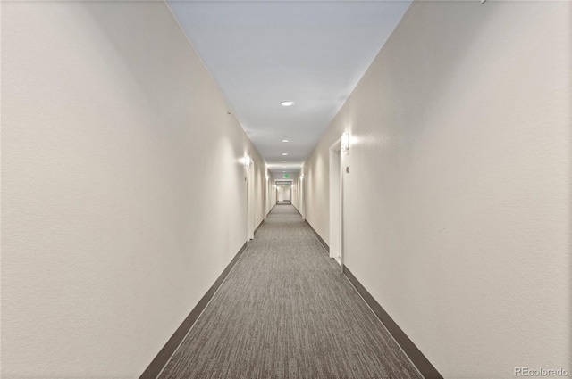 hall featuring baseboards and dark colored carpet