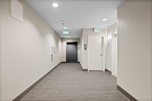 hallway featuring baseboards, elevator, and carpet floors