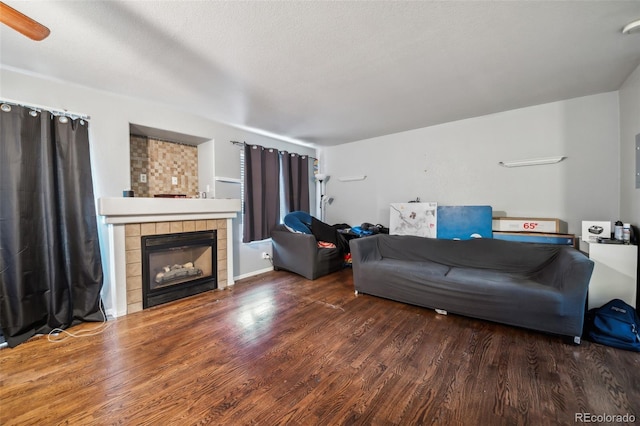 living room with a tile fireplace, a textured ceiling, and dark hardwood / wood-style flooring