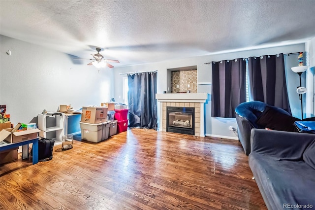 living room with hardwood / wood-style floors, ceiling fan, a textured ceiling, and a tile fireplace