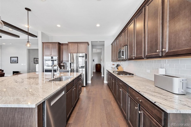 kitchen with stainless steel appliances, dark brown cabinetry, dark hardwood / wood-style flooring, light stone counters, and pendant lighting