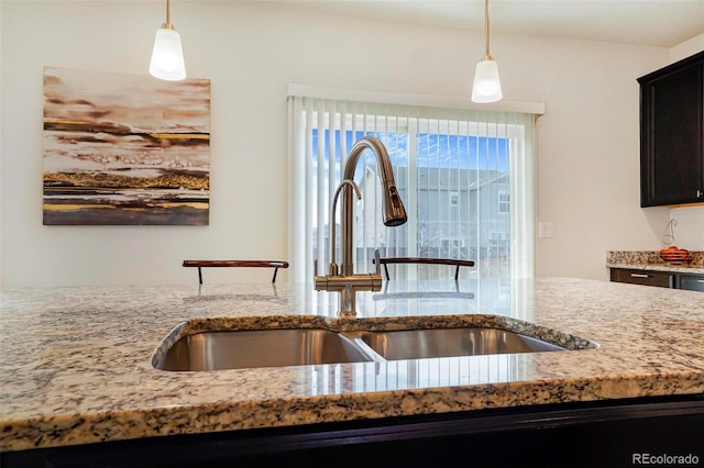 kitchen with hanging light fixtures, a sink, and light stone countertops