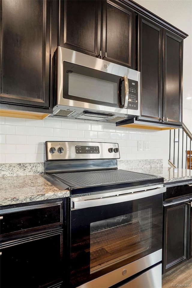 kitchen with appliances with stainless steel finishes, dark brown cabinetry, backsplash, and light stone countertops