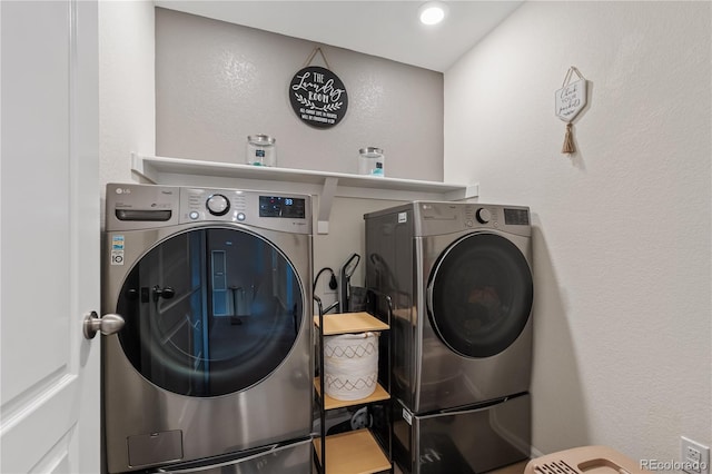 washroom featuring washer and dryer, laundry area, and a textured wall