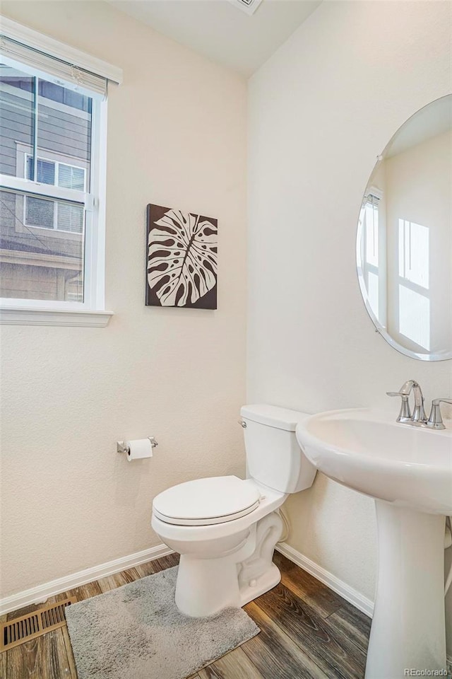 bathroom featuring toilet, a sink, baseboards, and wood finished floors