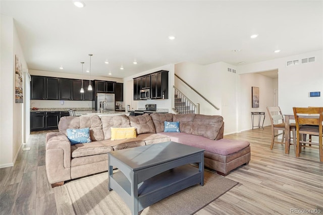 living area with light wood-type flooring, visible vents, and recessed lighting