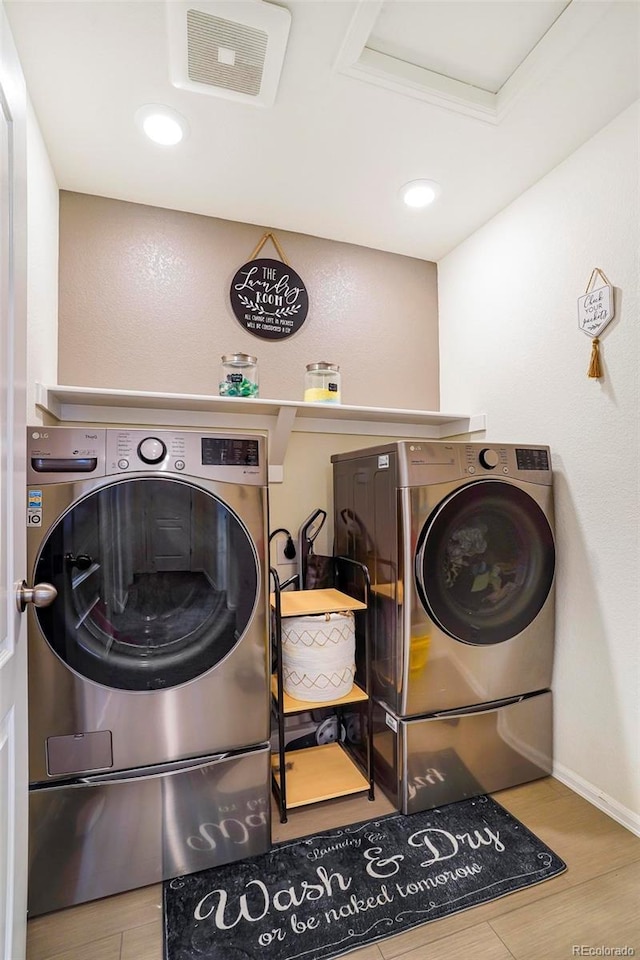 laundry room with laundry area, baseboards, visible vents, washer and clothes dryer, and wood finished floors