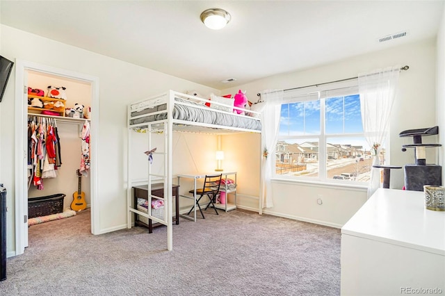 bedroom featuring carpet floors, baseboards, visible vents, and a walk in closet