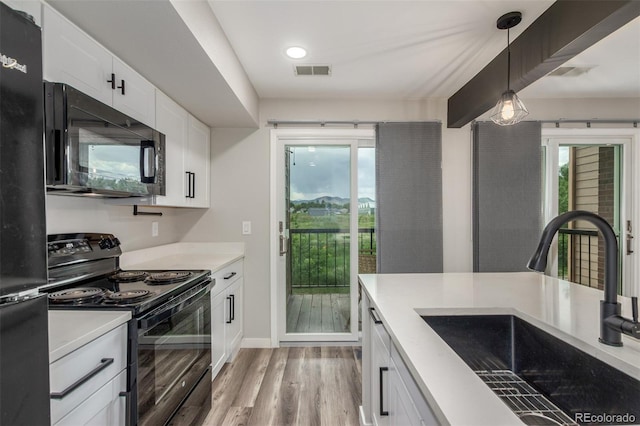 4899 S Dudley St Unit 14F, Littleton, CO 80123 - kitchen featuring black appliances, light countertops, light wood-style floors, white cabinets, and decorative light fixtures
