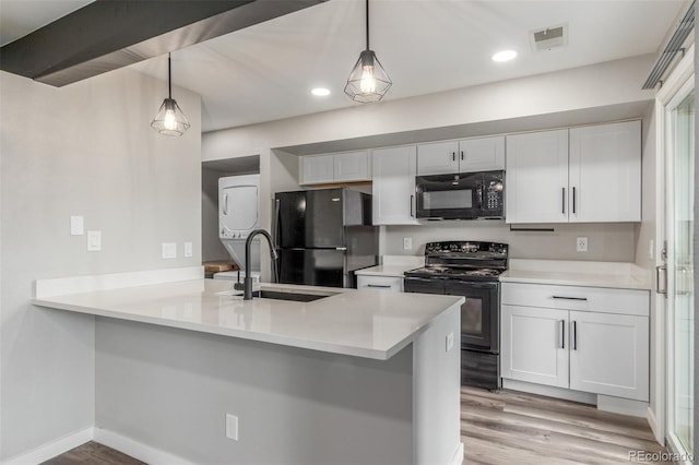4899 S Dudley St Unit 14F, Littleton, CO 80123 - kitchen featuring black appliances, stacked washer and clothes dryer, white cabinetry, light wood-style flooring, and a peninsula