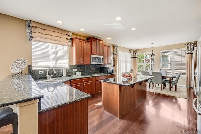 26764 E Canyon Ave, Aurora, CO 80016 - kitchen with stainless steel appliances, a kitchen bar, a sink, dark wood-style floors, and backsplash