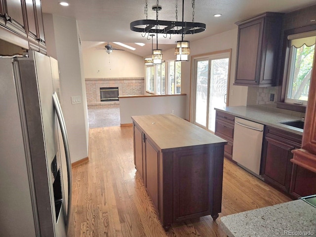 21064 E Crestline Cir, Centennial, CO 80015 - kitchen with stainless steel appliances, a fireplace, ceiling fan, a kitchen island, and light wood-style floors