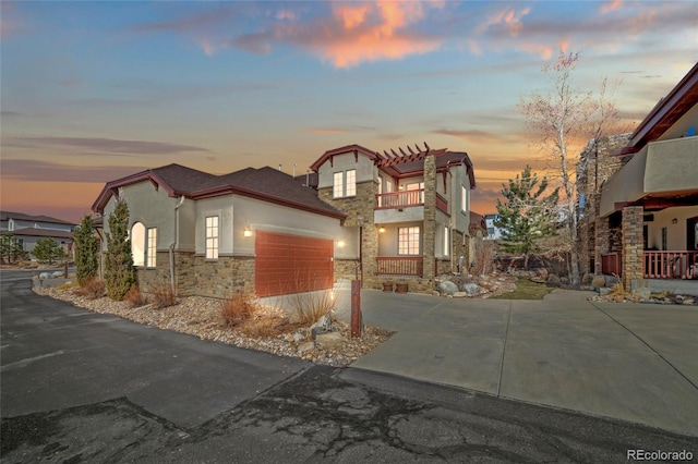 view of front of home featuring driveway, a pergola, stucco siding, a garage, and stone siding