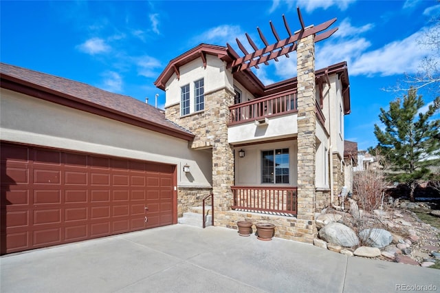 view of front of property featuring a balcony, a garage, stone siding, and stucco siding