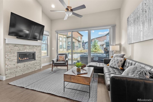 living room featuring ceiling fan, hardwood / wood-style flooring, and a tiled fireplace