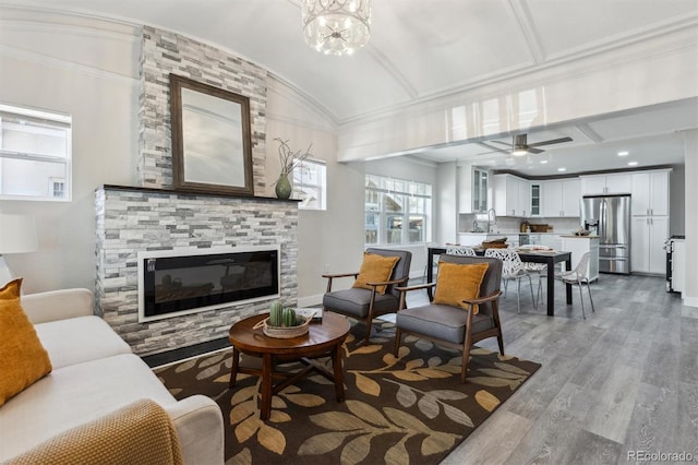 3929 Federal Blvd, Denver, CO 80211 - living room featuring a glass covered fireplace, wood finished floors, a ceiling fan, baseboards, and vaulted ceiling