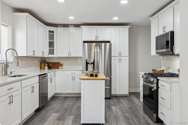 3929 Federal Blvd, Denver, CO 80211 - kitchen with appliances with stainless steel finishes, a sink, wood finished floors, white cabinetry, and recessed lighting