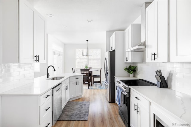 kitchen with sink, light hardwood / wood-style flooring, hanging light fixtures, stainless steel appliances, and white cabinets