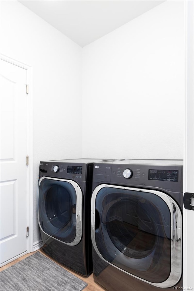 clothes washing area featuring washer and clothes dryer and light hardwood / wood-style flooring