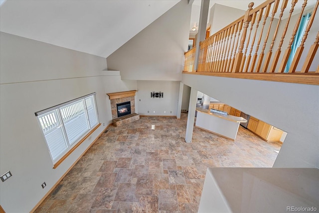 32800 E 137th Way, Brighton, CO 80603 - unfurnished living room featuring high vaulted ceiling, stone finish floors, baseboards, and a glass covered fireplace