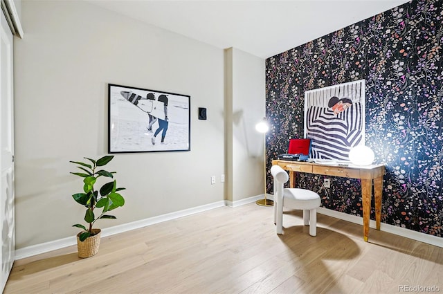 office featuring wood finished floors, baseboards, wallpapered walls, and an accent wall