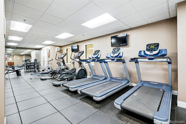 workout area featuring baseboards and a paneled ceiling