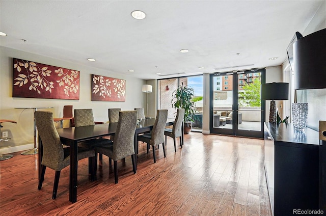 dining room with wood finished floors, recessed lighting, baseboards, and a wall of windows