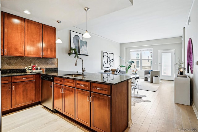 kitchen with stainless steel dishwasher, a sink, a peninsula, light wood-type flooring, and decorative backsplash