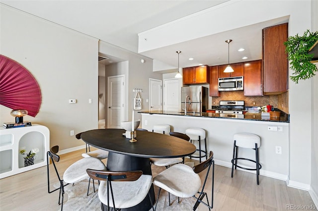 dining space featuring light wood finished floors, recessed lighting, and baseboards