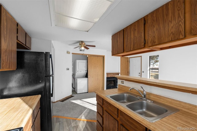 8701 Huron St Unit 5-210, Thornton, CO 80260 - kitchen featuring estacked washer and dryer, freestanding refrigerator, light countertops, a ceiling fan, and brown cabinetry