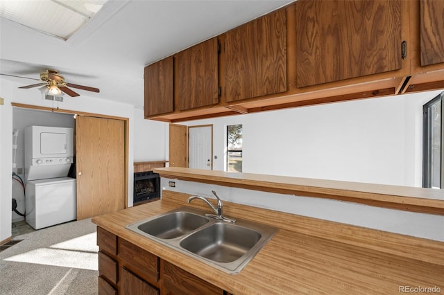 8701 Huron St Unit 5-210, Thornton, CO 80260 - kitchen with stacked washing machine and dryer, light countertops, ceiling fan, and brown cabinetry