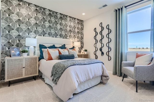 bedroom with visible vents, recessed lighting, wallpapered walls, light colored carpet, and an accent wall