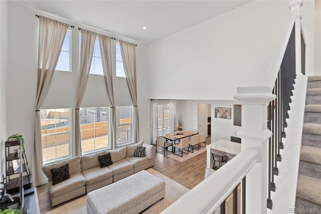 living area with stairway, recessed lighting, wood finished floors, and a wealth of natural light