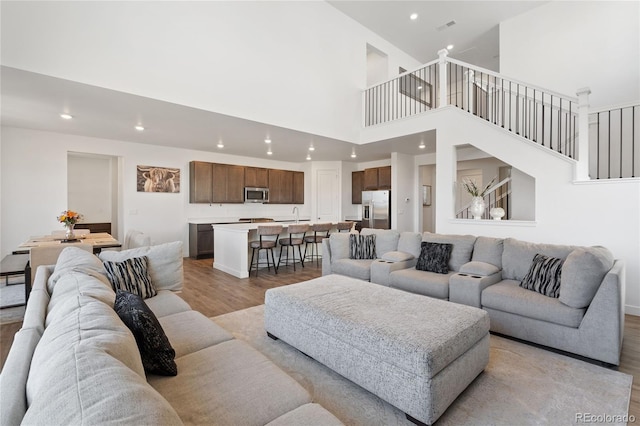 living room featuring stairway, wood finished floors, visible vents, a high ceiling, and recessed lighting