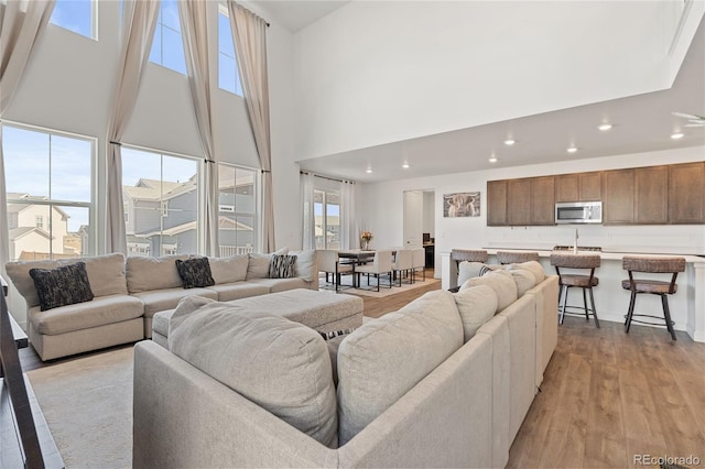 living area with light wood-style flooring, recessed lighting, and a high ceiling