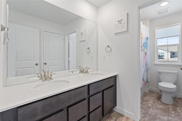 full bath with a sink, visible vents, toilet, and double vanity