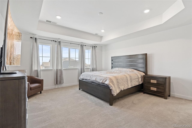 bedroom with a tray ceiling, baseboards, visible vents, and light carpet