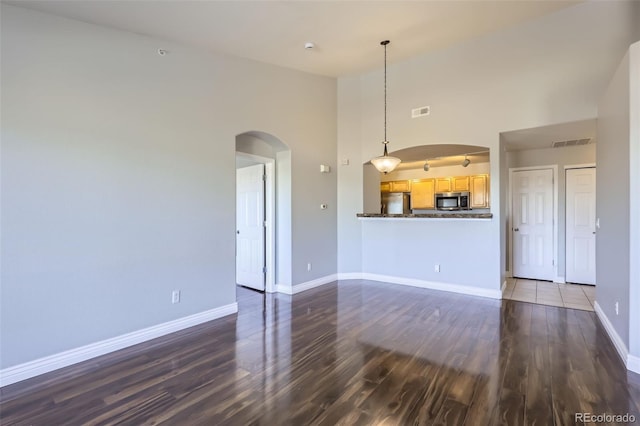 unfurnished living room with a high ceiling and dark hardwood / wood-style floors