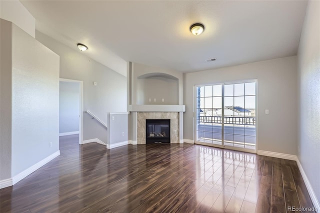 unfurnished living room with dark hardwood / wood-style floors, vaulted ceiling, and a tile fireplace